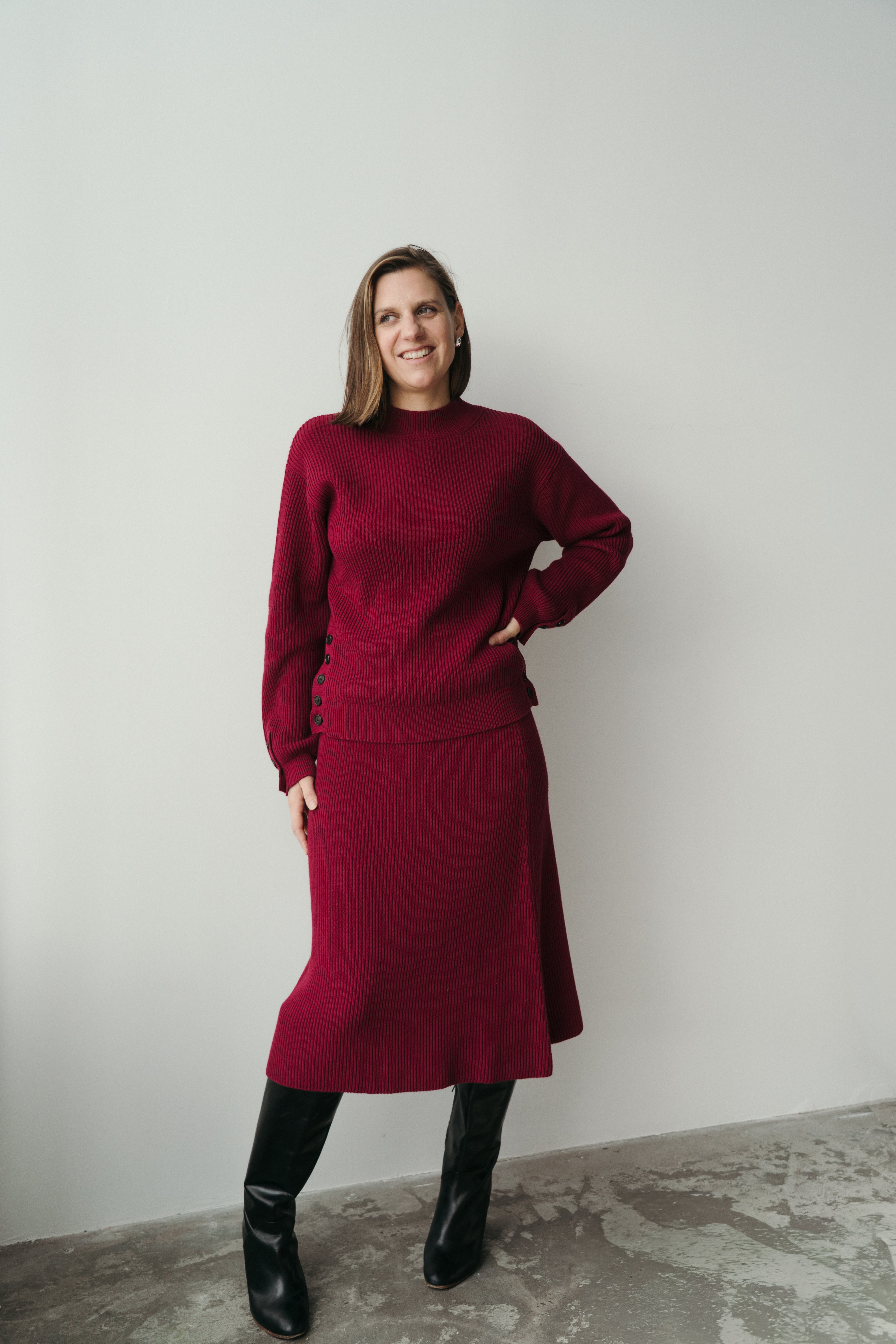 femme debout contre un mur avec un pull et une jupe assortie