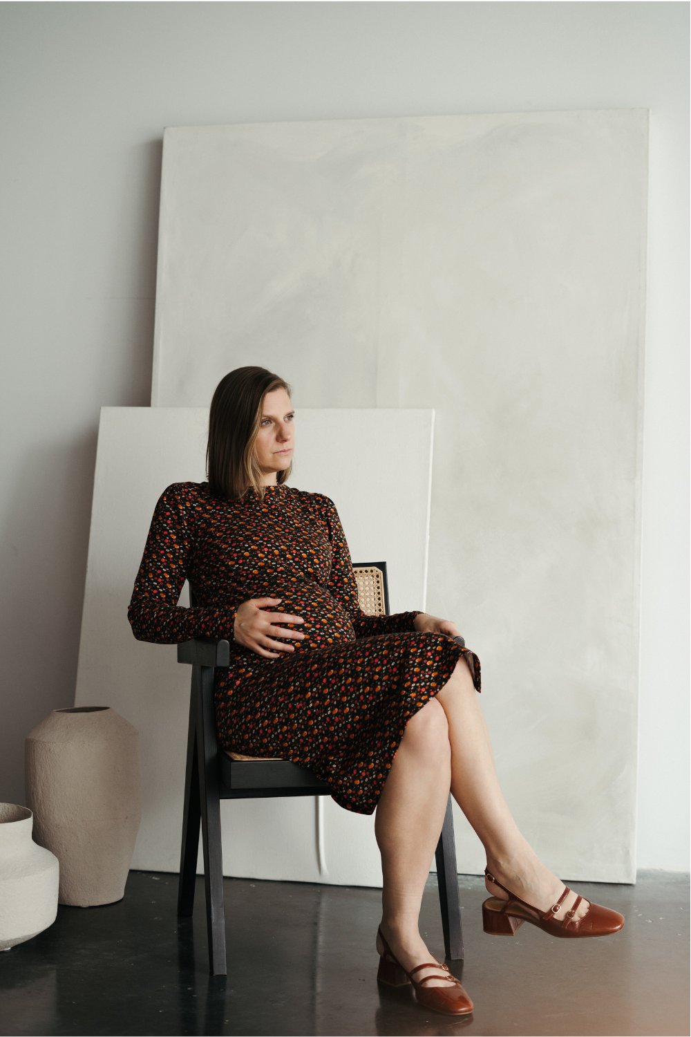 Femme enceinte qui porte une robe de grossesse fleurie assise.