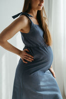 Femme allaitante en robe bleue fluide dans un intérieur clair et lumineux