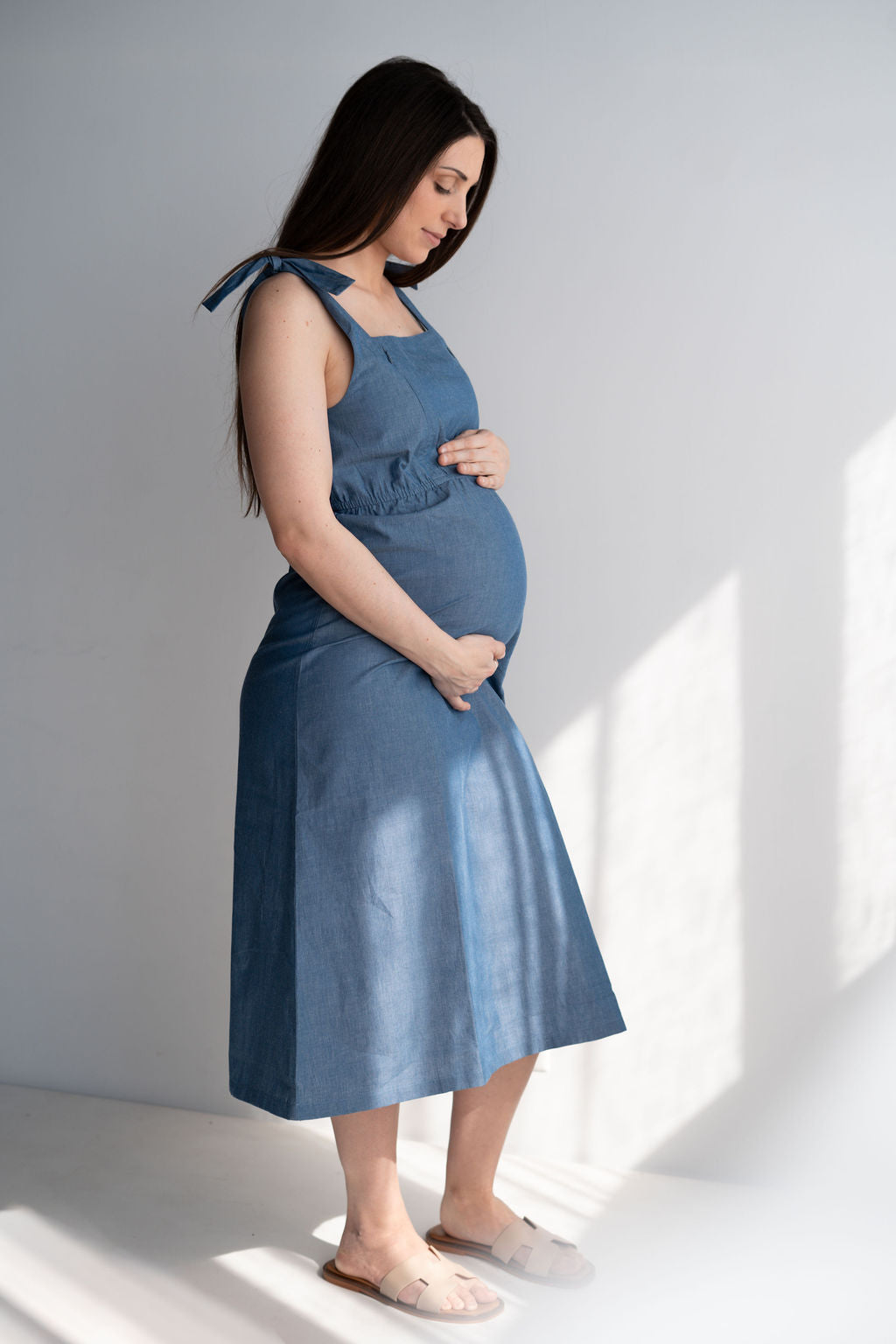 Femme enceinte en robe d'allaitement bleue coton marchant dans un décor naturel