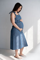 Femme enceinte en robe d'allaitement bleue coton marchant dans un décor naturel
