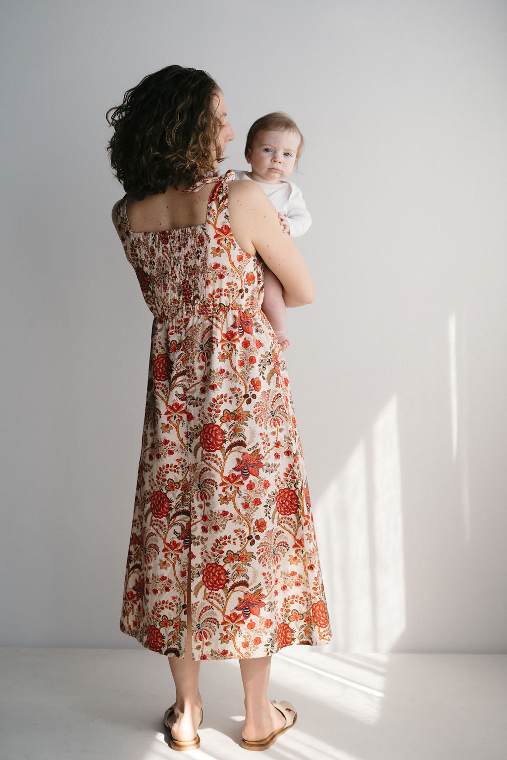 Femme en robe d'allaitement bohème imprimée rouge vert beige dans un décor extérieur