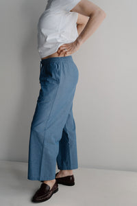 Femme enceinte debout en pantalon de maternité bleu uni élégant