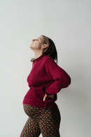 Femme enceinte qui se masse le dos et porte un chandail de maternité