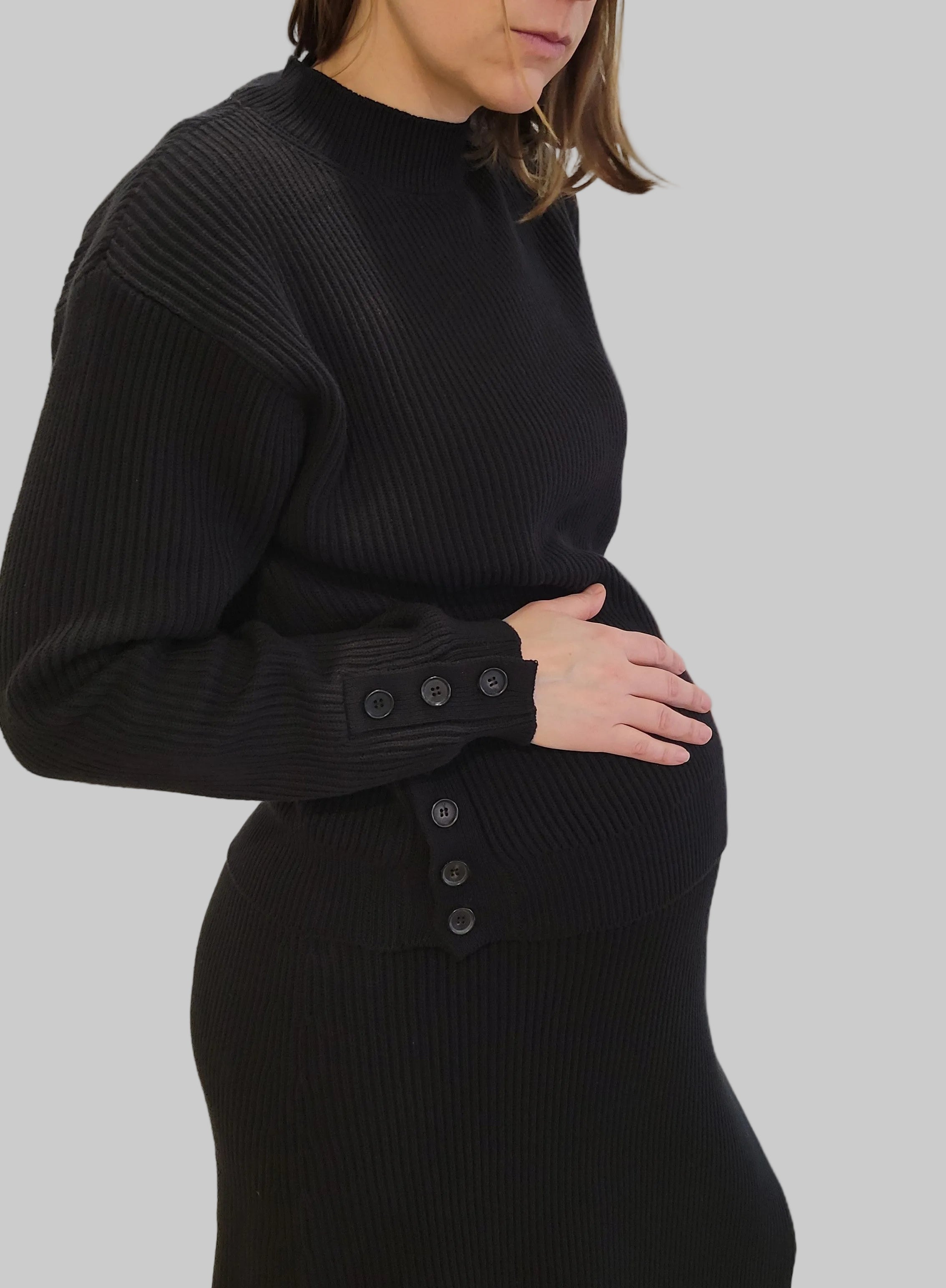 femme qui porte une robe et un pull noire de maternité en maille de coton