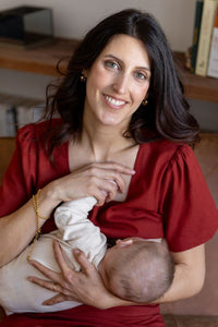 Femme qui allaite en souriant dans son haut de maternité