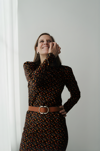 Femme qui porte une robe de 
 fleurie et noire et sourit