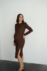 Femme enceinte qui porte une robe de maternité fleurie et sourit